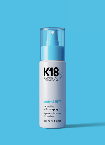 White and light blue bottle of Astrolift reparative volume spray on a blue background. 